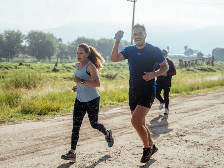 A group of runners enjoys a vibrant morning jog on a rural dirt road.